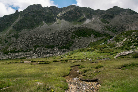 在高加索山脉的河流。山湖岸边的大石头。云在湖面上。石头上的雪