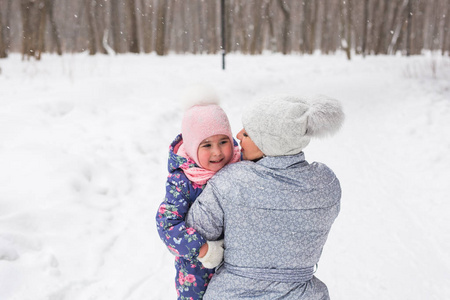 家庭, 儿童和自然概念年轻的母亲拥抱小快乐的孩子在冬季公园