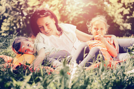 母亲和女儿在公园里。他们坐在草地上, 笑着享受自由的时光。