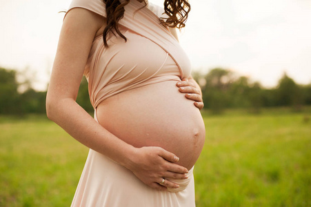 日落时怀孕妇女的腹部。怀孕的女孩感觉婴儿