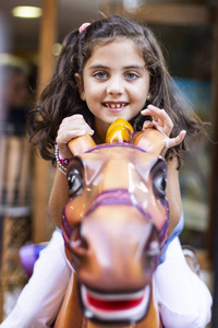 美丽的小女孩骑着马在嘉年华