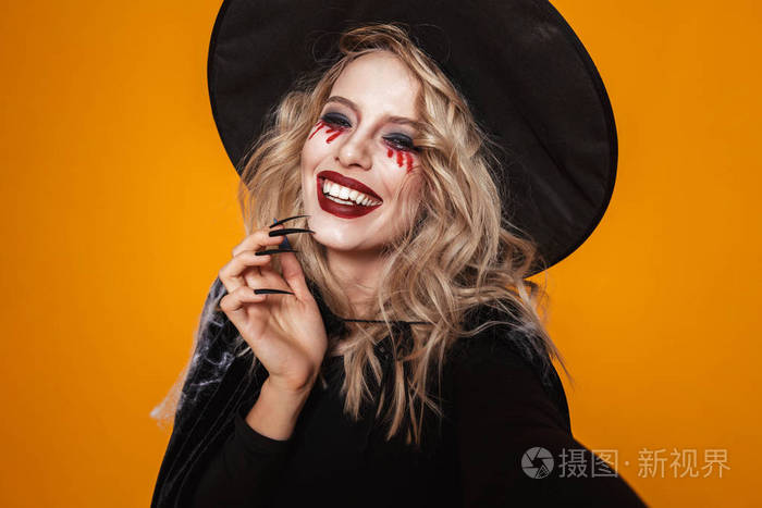 照片 节日,活动 金发碧眼的可怕的女人女巫的肖像在黑色帽子看相机和