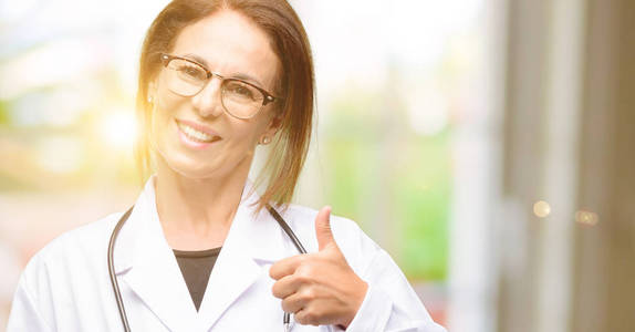 医生的女人, 医疗专业的微笑广泛显示竖起大拇指手势相机, 表达的喜欢和批准