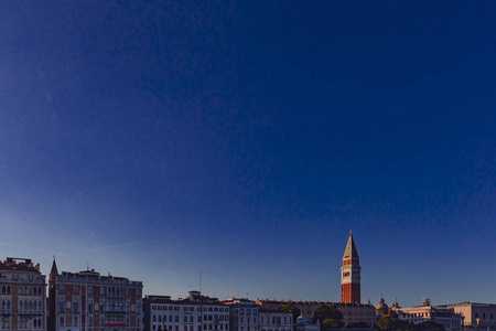 在日落时, 在蓝天下的威尼斯房屋上可以看到圣马克钟楼, 意大利威尼斯
