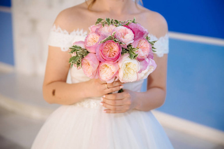 一个被裁剪的婚礼框架的特写是新娘手中的一束玫瑰花。穿着婚纱的女孩拿着花