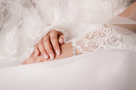新娘的手上披着花边面纱的连衣裙。美丽的手镯