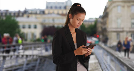 在巴黎旅行时的漂亮女商人在外面用手机发短信