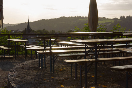 啤酒花园长凳和伞下的大橡树在一个暑假晚上日落前在德国南部