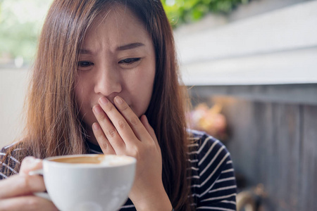 亚洲妇女手持热咖啡的特写图像在咖啡馆里感觉怪怪的和难闻的气味