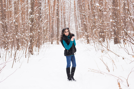 年轻漂亮的女人走在冬季雪公园在阳光明媚的一天