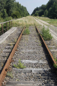一条废弃的旧铁路线, 有锈迹斑斑的铁轨和杂草丛生的睡眠者
