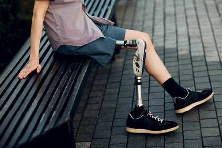 残疾青年脚假体坐在户外图片