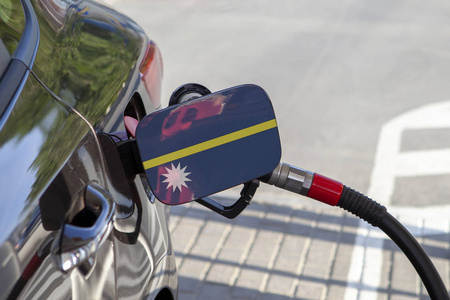 瑙鲁的旗子在汽车的油箱填料皮瓣。加油站用汽油泵加油的汽车。加油站。汽油和石油产品。特写