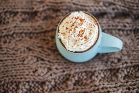 一杯咖啡可可粉或热巧克力, 上面有奶油和肉桂的围巾。南瓜拿铁寒冷的秋天或冬天的舒适饮料