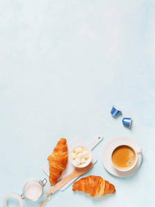 咖啡浓缩咖啡的顶部视图与胶囊, 羊角面包和黄油在蓝色柔和的背景