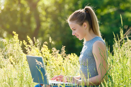 一个女孩在绿色的草地上自然的笔记本电脑