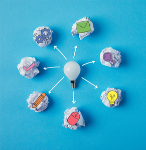 灯泡的顶部视图被皱巴巴的纸围绕在蓝色表面上的商业图标