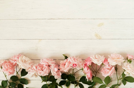 在白色木质背景美丽的粉红色玫瑰花束框架。顶部视图。复制空间