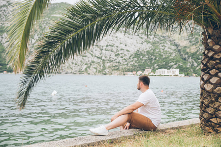 坐在海边, 风景秀丽的男子。山上的背景。夏季时间