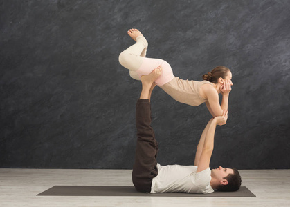 年轻夫妇在垫子上练习 acroyoga