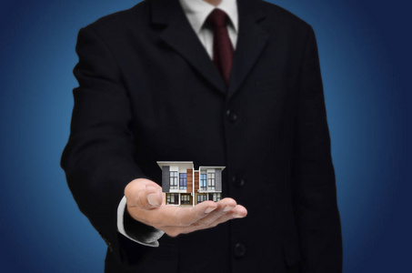商人在他的手上展示一个房子的缩影作为一个概念的财产投资或住房