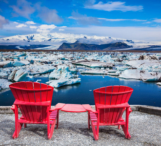 两个红色甲板椅子欣赏漂移冰 Jokulsarlon。冰岛冰礁湖极端北方旅游的概念
