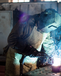 焊工在工厂的焊接口罩焊缝金属零件, 焊接和火花