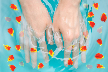 女性双手与花瓣在水中。特写