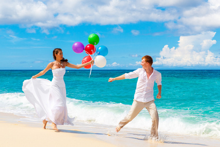 幸福的新娘和新郎在地处热带的海滩上尽情的