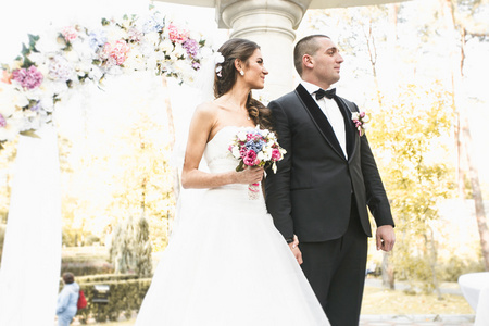 幸福新婚夫妇站在花拱下