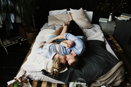 年轻浪漫情侣的快乐早晨在卧室里有乐趣, 亲吻和拥抱。爱和关系生活方式, 室内黑色阁楼卧室