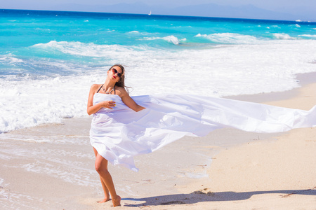 白色织物在海滩上的漂亮女孩