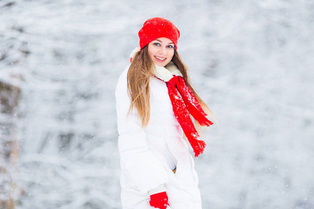 美丽的女孩可爱的笑容, 看着相机镜头下降雪和雪公园的背景