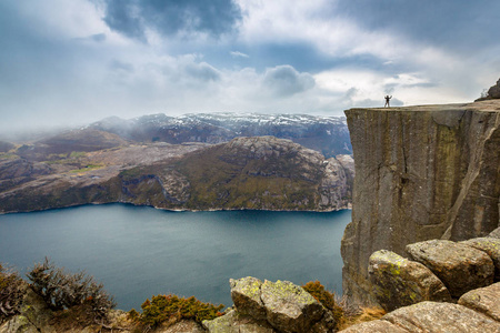 人站立在讲坛岩石的峭壁 Preikestolen, 挪威