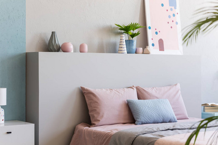 床上的床头贴着粉红色枕头的海报, 里面有植物。真实照片