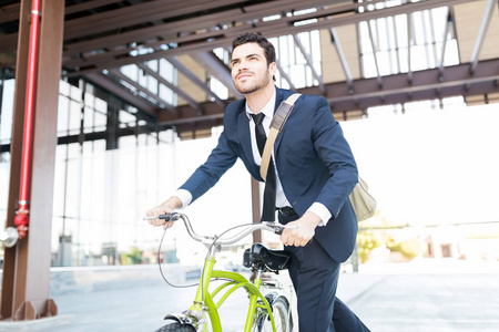 坚定的经理在优雅的西装骑老式自行车在城市