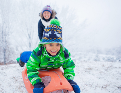 小男孩玩雪橇在冬季公园