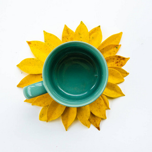空咖啡杯与创意安排黄叶. 由黄叶和咖啡杯制成的向日葵. 平躺