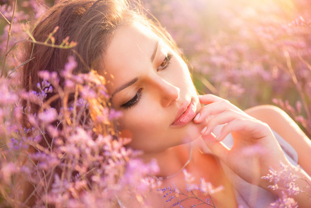 美丽的女孩躺在一片草地上，紫罗兰色的花朵