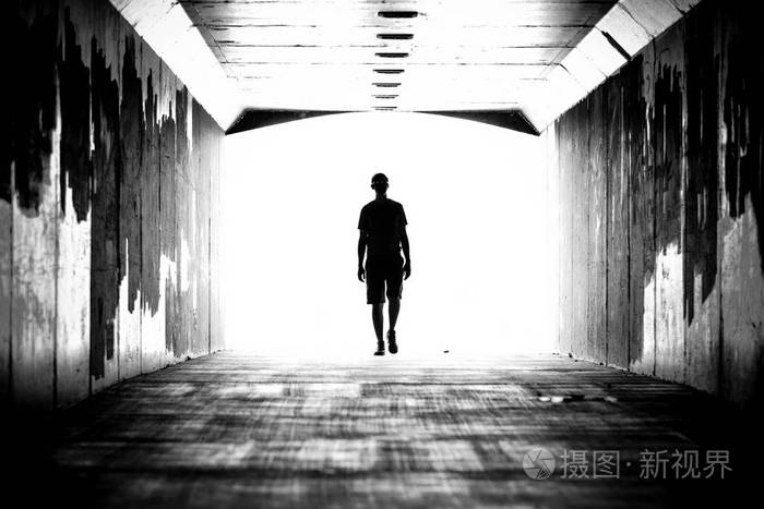 一个人在隧道的剪影, 向前走.明亮的灯光照耀在背景中