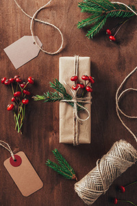 平放置与圣诞礼物冷杉分支, 装饰浆果, 绳子和标签在木背景