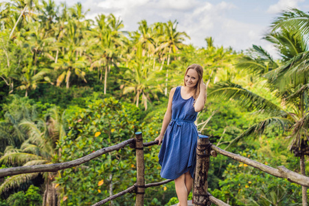 位于印尼巴厘岛的年轻女子旅行者在风景点上摆出丛林背景