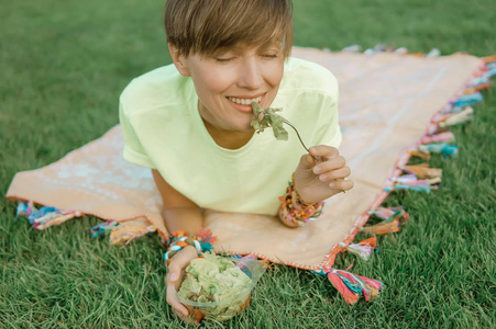 白种人妇女吃沙拉的画像坐在绿草自然背景