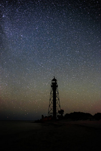 旧灯塔的剪影沙滩和海洋对星空的背景