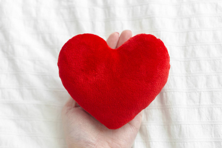 红色心脏在手在白色纺织品, 情人节概念