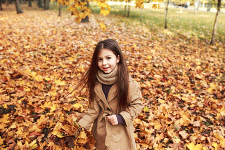 小女孩在秋叶玩耍