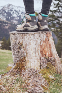 女性经典真皮登山靴的特写在山上的树桩上穿的妇女旅行和户外活动概念