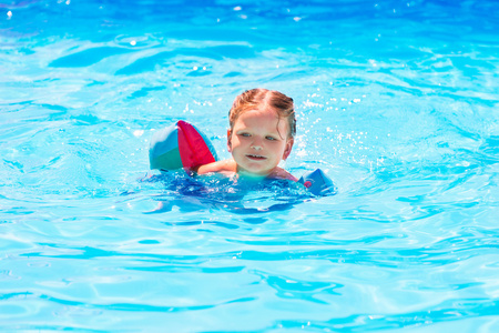 女婴在游泳池里与漂浮袖子