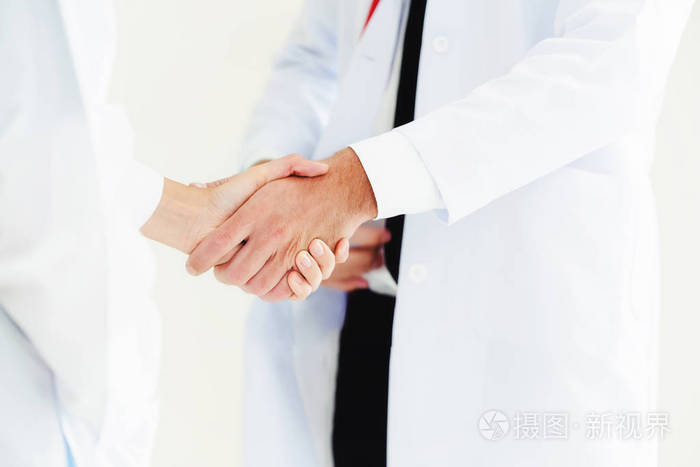 医生在白色背景下, 与另一位医生握手, 展示了专业医护人员的成功和