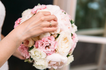 特写镜头, 新娘穿着白色连衣裙, 拿着她的结婚花束, 向相机展示鲜花。婚礼日, 新娘花束